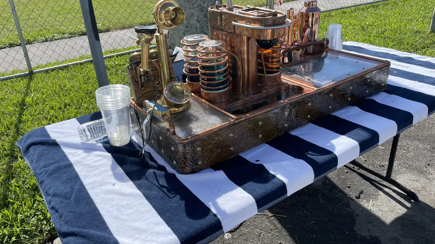 The machine set up outdoors on a folding table with a striped cloth