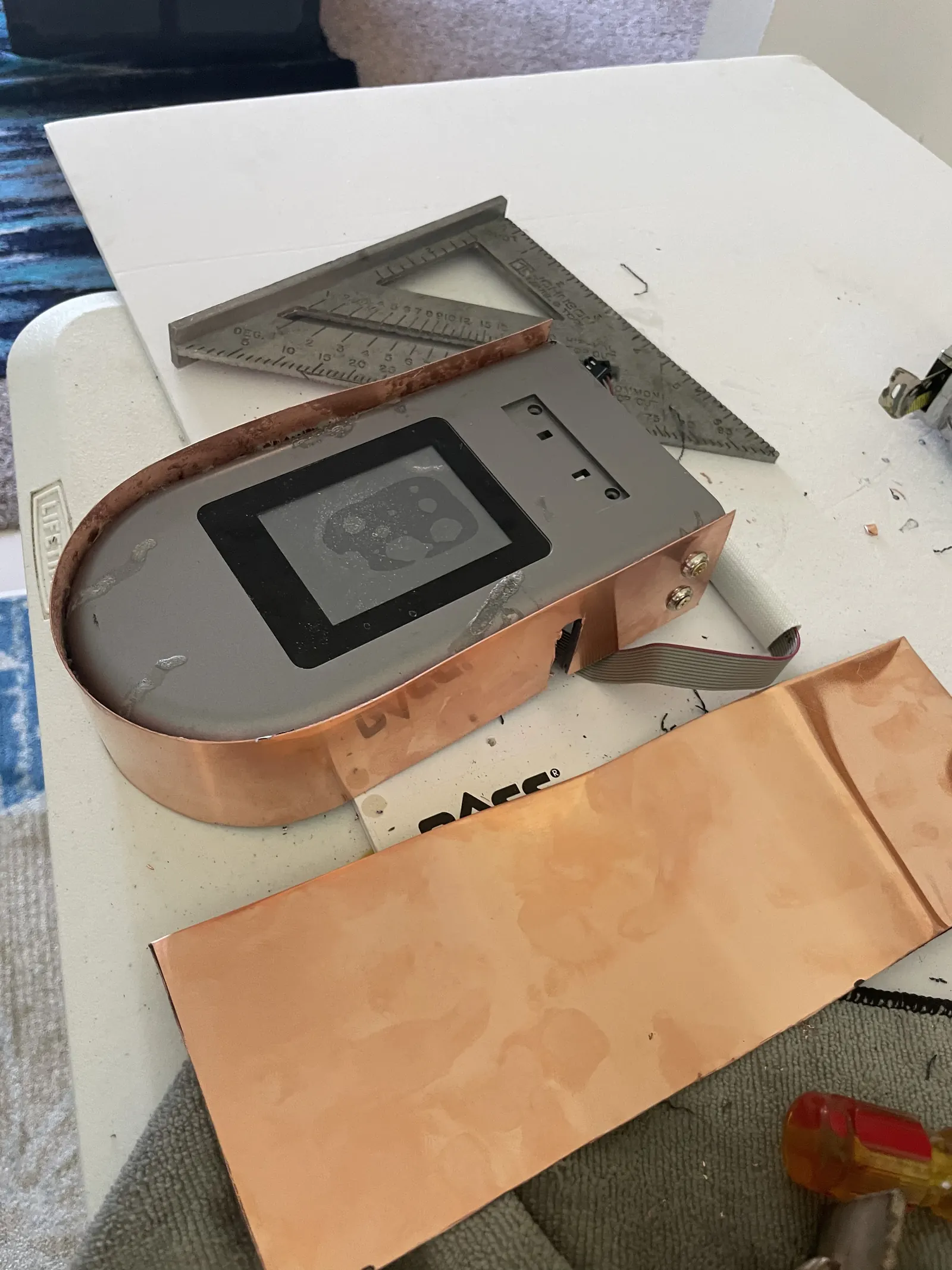 Cut copper sheet pieces beside the machine's screen frame