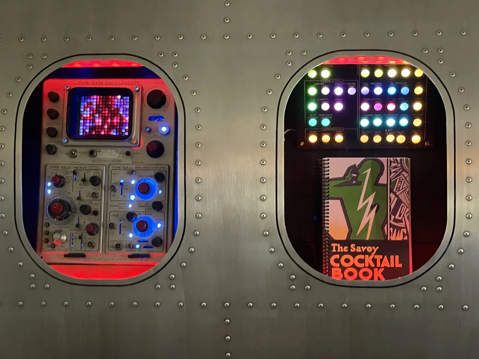 The jukebox panel with lit dot-matrix display beside the cocktail book