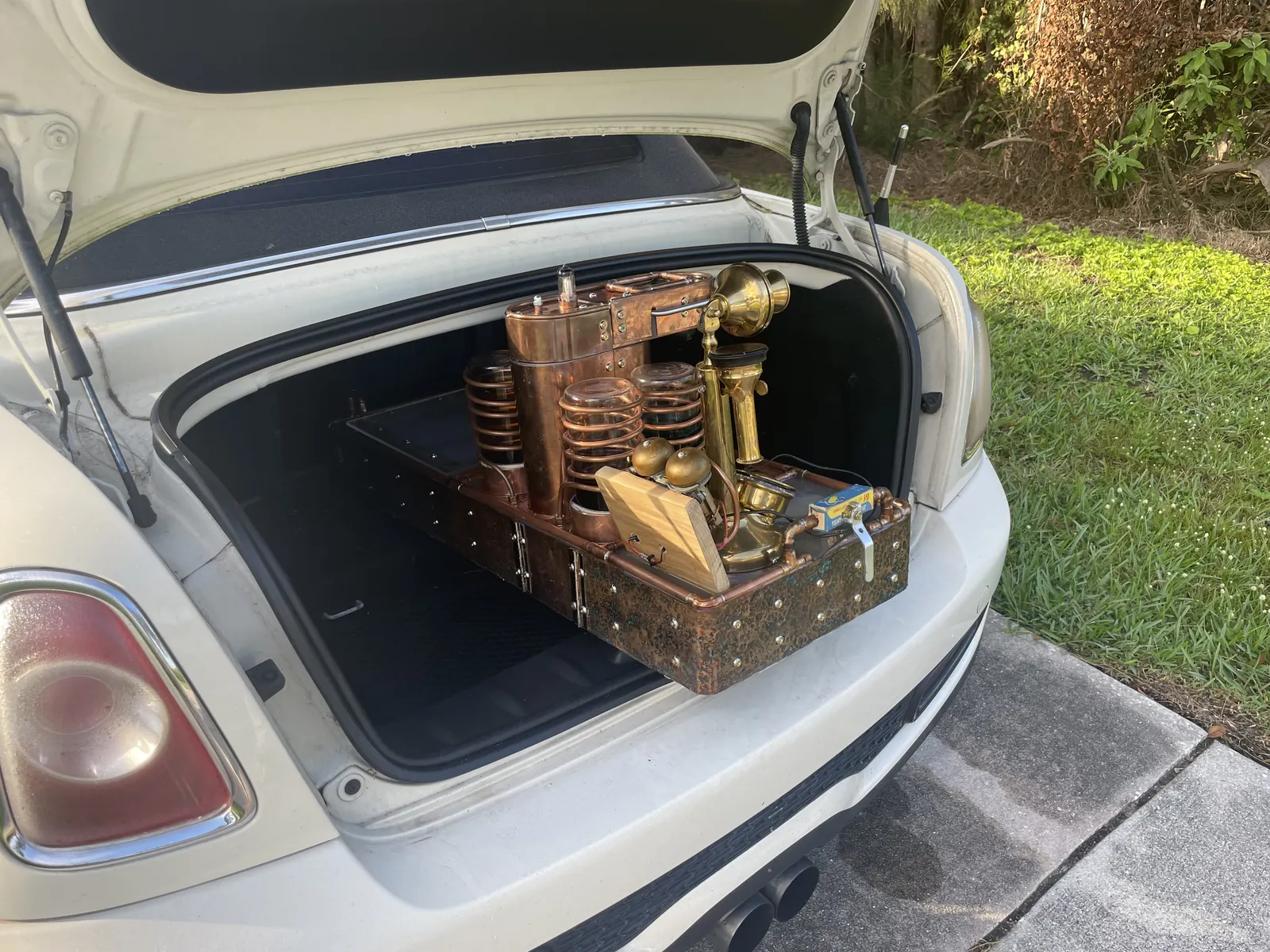 The machine riding in the open trunk of a car