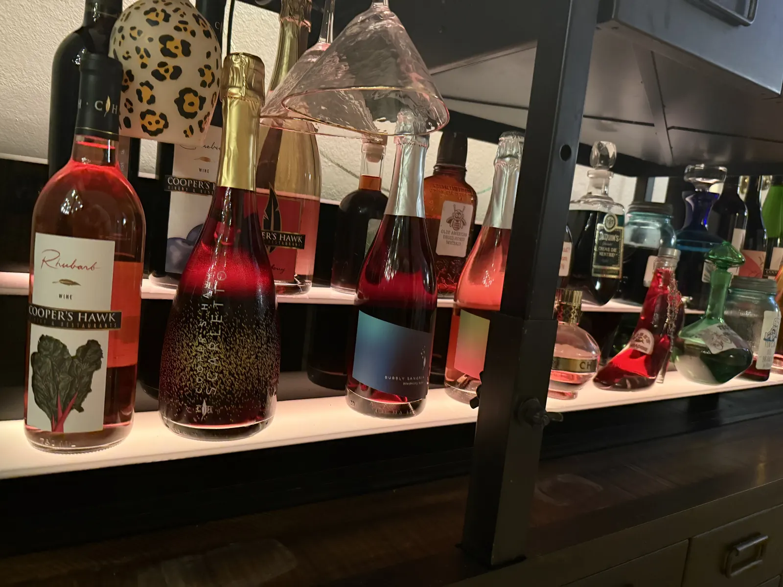A lit shelf of wine and spirits bottles