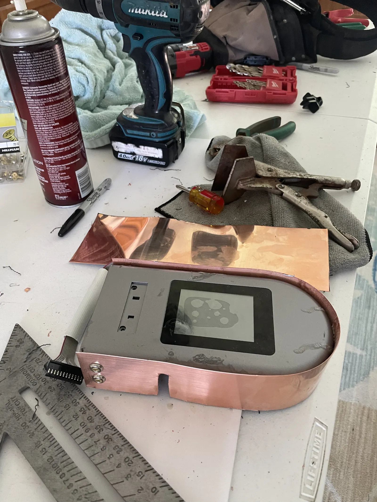 A workbench covered in copper pieces, a drill and tools